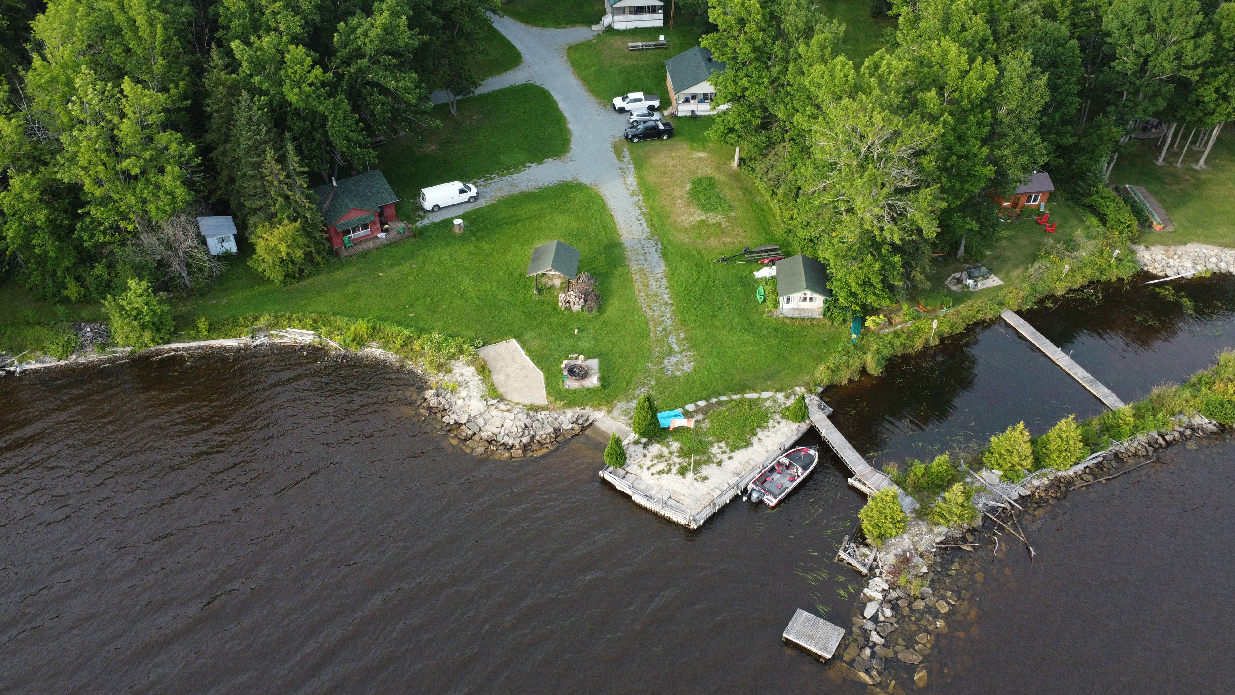Aerial view showing the Property at the water's edge — cottages, lawn, private stone breakwall, dock and boat