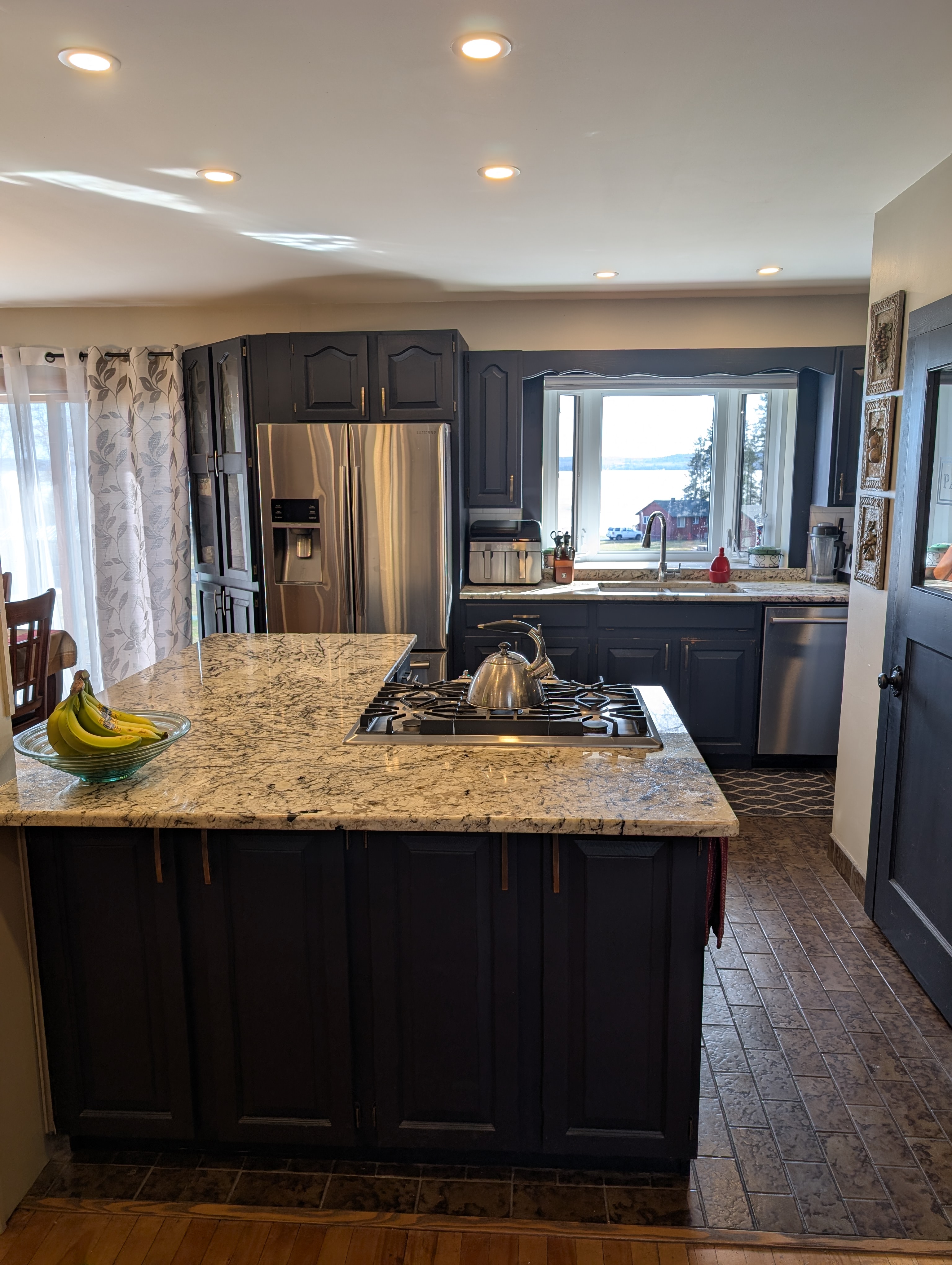 Main residence kitchen — granite countertops, gas cooktop, stainless steel appliances, custom cabinetry, and a window view of Lake Timiskaming