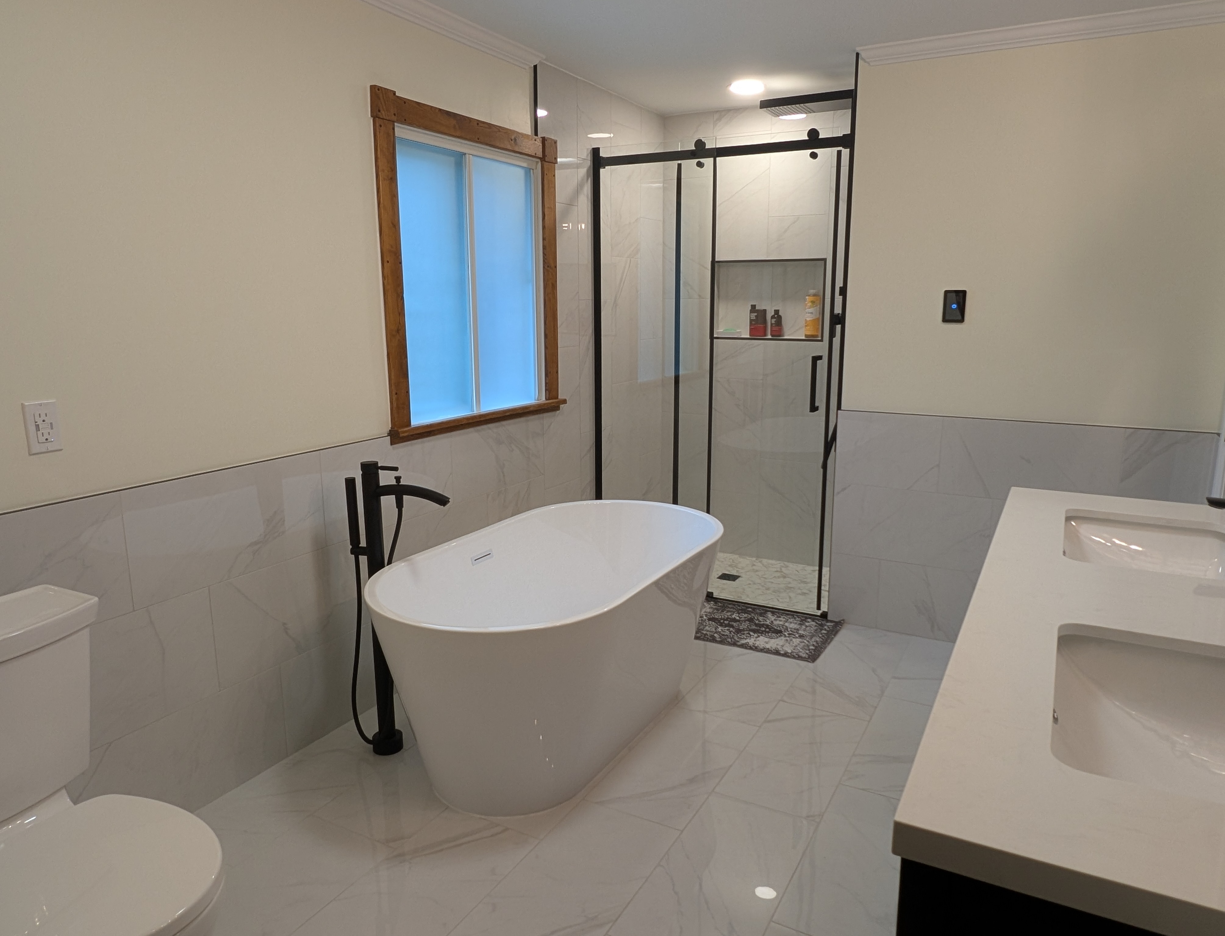 Main residence master bath — freestanding tub, glass shower with marble tile, double vanity